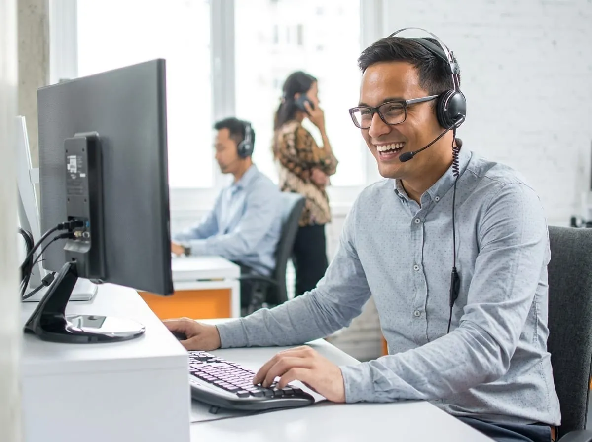 Staf dukungan mengenakan headset bekerja di depan monitor